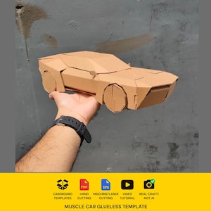 Op de afbeelding: Een bruin kartonnen model van een muscle car met een geometrisch, hoekig ontwerp, een laag profiel, een plat dak en ronde wielen. Het model is opgebouwd uit gevouwen kartonnen onderdelen en toont een lijmvrije constructie.