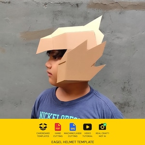 Può includere: Un casco da aquila in cartone color marrone chiaro dal design geometrico e spigoloso, con becco appuntito e piume stilizzate. Il banner giallo in basso mostra icone per modelli in cartone, PDF, SVG, video tutorial e artigianato reale, con il testo EAGEL HELMET TEMPLATE.