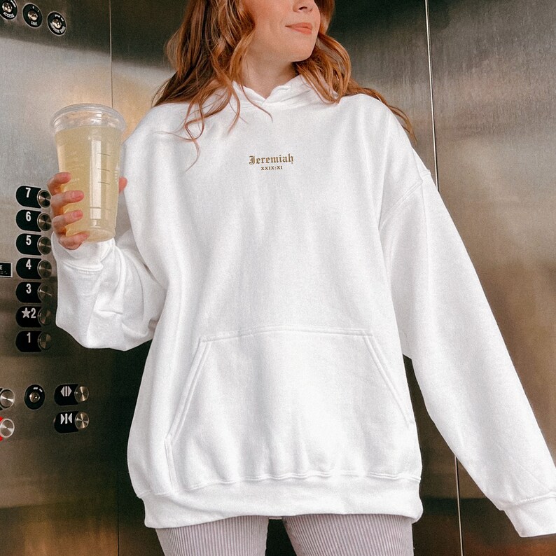 May include: White oversized hoodie with a gold embroidered logo that says "Jeremiah XXIII:XI".