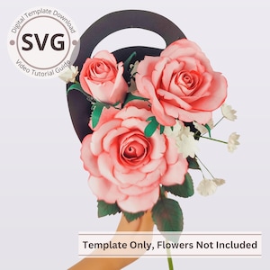 Op de afbeelding: Een boeket van grote roze papieren rozen met groene bladeren en kleine witte bloemen. De bloemen worden vastgehouden in een zwarte handgreep. De tekst "SVG" en "Template Only, Flowers Not Included" is inbegrepen.