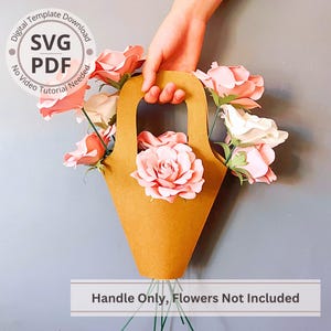 Puede incluir: Una cesta de flores de papel marrón con asa, llena de rosas de papel rosas y blancas. El texto "Handle Only, Flowers Not Included" está en la parte inferior. La imagen también incluye el texto "SVG PDF Digital Template Download No Video Tutorial Needed".