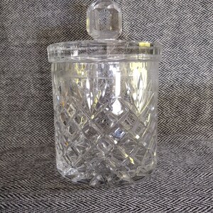 May include: A clear glass jar with a diamond pattern and a clear glass lid. The jar has a round shape and a smooth surface.