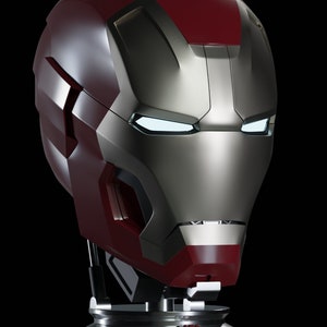 May include: A red and silver Iron Man helmet replica with a detailed design and glowing eyes. The helmet is mounted on a black base with a circular design.