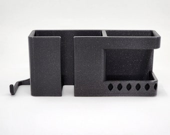 May include: A black plastic organizer with multiple compartments and a hook. The organizer has a textured surface and is designed to hold various items.