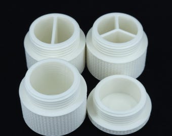 May include: Four white plastic containers with different compartment configurations. The containers have a textured exterior and are designed for storing small items.