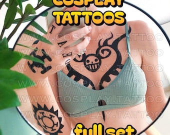May include: A set of black temporary cosplay tattoos applied to the chest, hand, and forearm. The designs include a heart-shaped emblem with a skull, a sun-like circular symbol, and lettering on the fingers. The text reads TEMPORARY COSPLAY TATTOOS and full set + GIFTS!