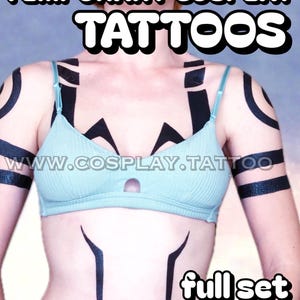 Może przedstawiać: Tymczasowe tatuaże z czarnego tuszu z odważnymi geometrycznymi liniami na klatce piersiowej, ramionach i brzuchu. Tekst TEMPORARY COSPLAY TATTOOS, WWW.COSPLAY.TATTOO oraz full set + gifts! jest nałożony na obraz. Widoczny jest jasnoniebieski prążkowany biustonosz.