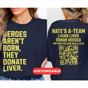 May include: Dark blue t-shirt with yellow text: "HEROES AREN'T BORN, THEY DONATE LIVER." The back of the shirt reads "NATE'S A-TEAM LIVING LIVER DONOR NEEDED ASK HOW YOU CAN SAVE A LIFE!" with a QR code. The word "CUSTOMIZABLE" is on the bottom.