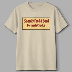 Może przedstawiać: Beżowa koszulka z prostokątnym wzorem znaku. Znak głosi "Sneed's Feed & Seed Formerly Chuck's" w kolorze czerwonym i brązowym, zaprojektowany tak, aby przypominał drewnianą deskę.
