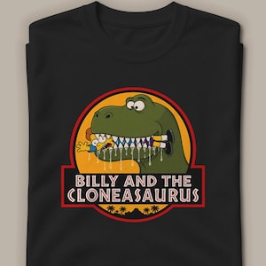 Op de afbeelding: Een zwart t-shirt met een afbeelding van een groene dinosaurus die een stripfiguur in zijn bek houdt. Het ontwerp bevat een oranje cirkel, een zwarte banner met de witte tekst "BILLY AND THE CLONEASAURUS" en een silhouet van palmbomen onderaan.