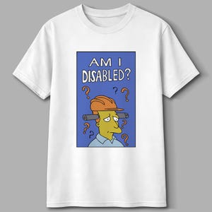 May include: White t-shirt featuring a cartoon image of a character with a construction hat and the text "AM I DISABLED?" in a blue rectangle. Question marks surround the character's head.