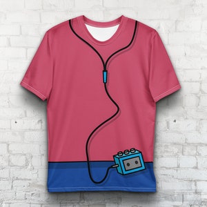 May include: A pink t-shirt with a blue and black cassette tape design. The cassette tape is connected to a black headphone cord that is hanging down the front of the shirt.