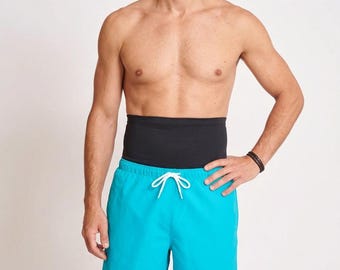 Peut inclure: Short de bain bleu turquoise vif doté d'un cordon de serrage blanc à la taille élastique, porté avec une large bande de compression abdominale noire située au-dessus de la ceinture du short.