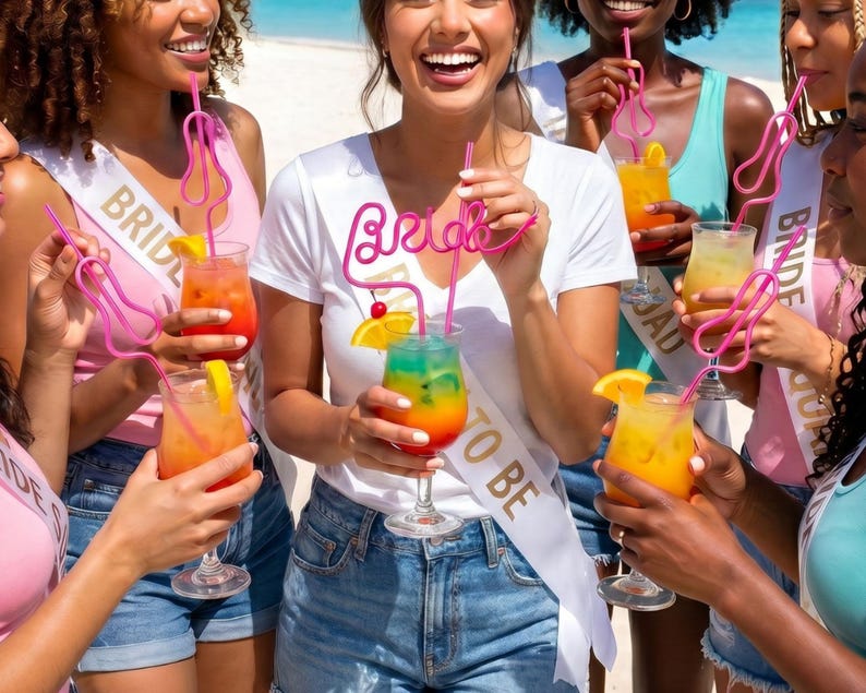May include: A group of people holding colorful cocktails with pink decorative straws. The cocktails have orange and yellow garnishes. Some people are wearing white sashes that say "Bride to Be".