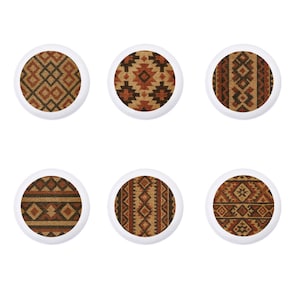 May include: Six white, circular cabinet knobs with various Southwestern-style geometric patterns in shades of brown, tan, and rust. The knobs feature a textured fabric appearance, adding visual interest to the design.