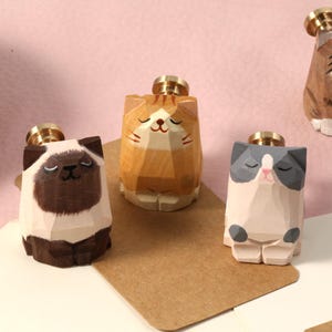 May include: A white ceramic mug with a black handle and the text "But First, Coffee" in a black, bold font. The mug is sitting on a white surface. The mug is approximately 4 inches tall.