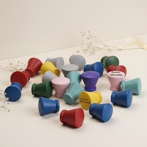 May include: A collection of colorful wooden cabinet knobs in various shapes and sizes. The knobs are painted in shades of red, blue, yellow, green, pink, and purple. Some knobs have the text "Custom affordable" printed on them.