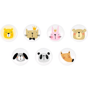 Puede incluir: Conjunto de siete botones redondos blancos con diferentes caras de animales. Los animales incluyen un león, un gato, un conejo, un oso, un perro, un panda y un zorro. Cada animal tiene un color y un diseño diferente.