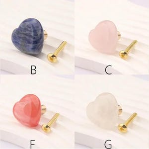 May include: A selection of heart-shaped cabinet knobs in different colours, such as red, blue, pink, and green. Each knob has a gold-coloured base and screw. The knobs are labelled A to H.