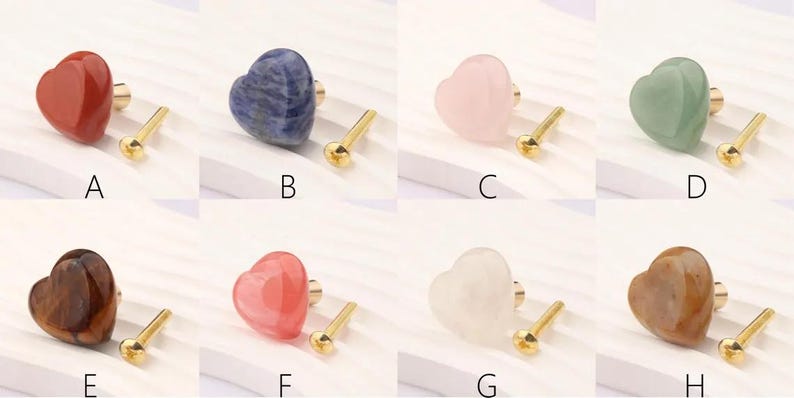 May include: A selection of heart-shaped cabinet knobs in different colours, such as red, blue, pink, and green. Each knob has a gold-coloured base and screw. The knobs are labelled A to H.