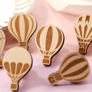 Op de afbeelding: Zes houten luchtballon ornamenten in verschillende ontwerpen. De ballonnen zijn allemaal bruin met witte accenten en zijn gemaakt van hout. Ze zijn perfect om een vleugje whimsy toe te voegen aan elke ruimte.