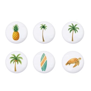 Könnte beinhalten: Sechs weiße Keramik-Schrankknöpfe mit tropischen Designs. Die Knöpfe zeigen eine Ananas, Palmen, ein Surfbrett und eine Meeresschildkröte. Die Illustrationen sind im Aquarellstil gehalten, mit einer hellen und fröhlichen Farbpalette.