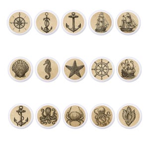 May include: A collection of nautical-themed decorative buttons. Each button features a different design, including a compass rose, anchors, sailboats, a seashell, a seahorse, a starfish, a ship's wheel, an octopus, and a crab. The designs are in black and white on a tan background.