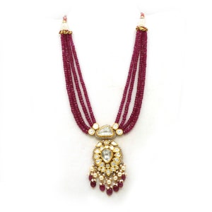 May include: A multi-strand necklace with a gold pendant featuring a large, clear gemstone surrounded by smaller gemstones. The necklace is made of red beads.
