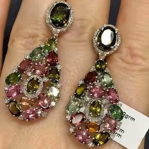 Puede incluir: Un par de pendientes colgantes en forma de lágrima. Los pendientes están hechos de plata y presentan un grupo de piedras preciosas de colores, incluyendo rosa, verde y marrón. Las piedras preciosas están engastadas en pavé.