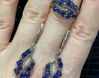 May include: A set of sapphire and diamond earrings and ring. The earrings are dangle style with a cluster of blue sapphires and white diamonds. The ring is a band with a cluster of blue sapphires and white diamonds.