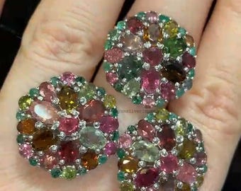 Puede incluir: Tres anillos redondos con un grupo de piedras preciosas de colores. Los anillos están engastados en plata y presentan una variedad de piedras preciosas rosas, verdes y marrones.
