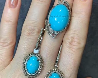 May include: A turquoise and diamond ring and earrings set. The ring and earrings feature oval-shaped turquoise stones surrounded by a halo of diamonds.