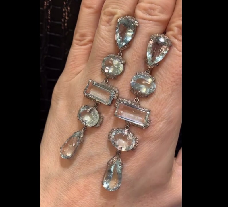May include: A pair of long, silver dangle earrings with multiple aquamarine gemstones and diamond accents. The earrings feature a teardrop-shaped gemstone at the bottom, followed by a rectangular gemstone, a round gemstone, and a teardrop-shaped gemstone at the top.