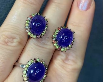 May include: A set of two rings featuring a large oval purple gemstone surrounded by a halo of smaller green, red, and yellow gemstones.