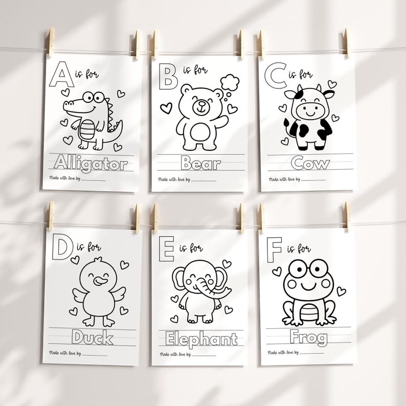 May include: Six white paper prints with black line drawings of animals and the alphabet. Each print features a different animal: alligator, bear, cow, duck, elephant, and frog. The prints are hanging from wooden clips.
