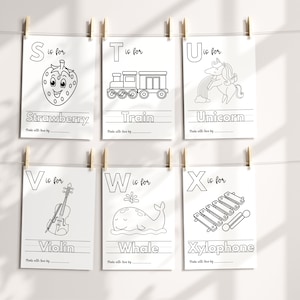 May include: Black and white printable alphabet flashcards featuring a letter, an illustration, and the word for the illustration. The letters are S, T, U, V, W, and X. The illustrations are a strawberry, a train, a unicorn, a violin, a whale, and a xylophone.
