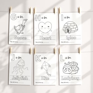 May include: Black and white printable alphabet flashcards featuring a goose, heart, igloo, jellyfish, kite, and ladybug. Each card has a letter, the word for the image, and a line for writing.