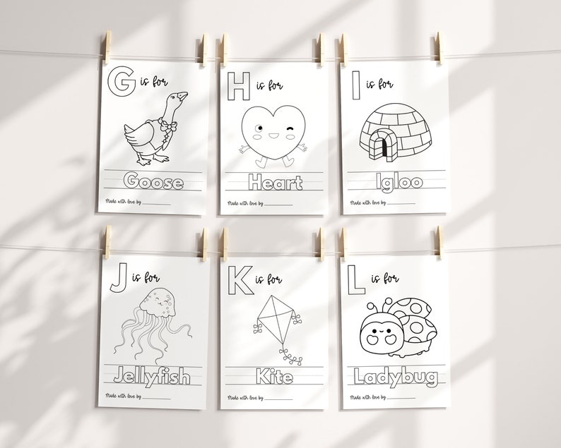 May include: Black and white printable alphabet flashcards featuring a goose, heart, igloo, jellyfish, kite, and ladybug. Each card has a letter, the word for the image, and a line for writing.