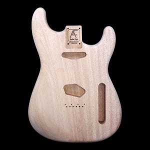 Könnte beinhalten: Unbehandelter Gitarrenkorpus aus Naturholz mit einem Ausschnitt für den Hals und einem Tonabnehmer. Der Korpus trägt ein Etikett mit dem Text "AF Guitar Shop C000388".