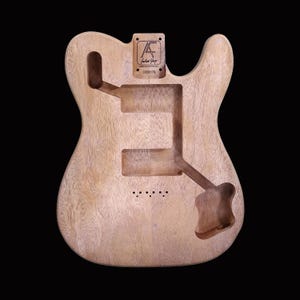 May include: Unfinished natural wood guitar body with a cutout for the neck and a pickup. The body is labeled "Artist Guitar" and "C000179".