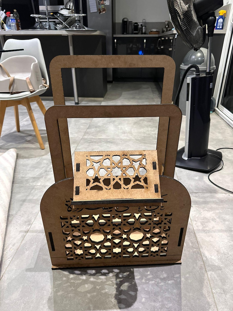 May include: A wooden decorative shelf with intricate geometric patterns cut into the wood. The shelf has two levels and is made of light brown wood.