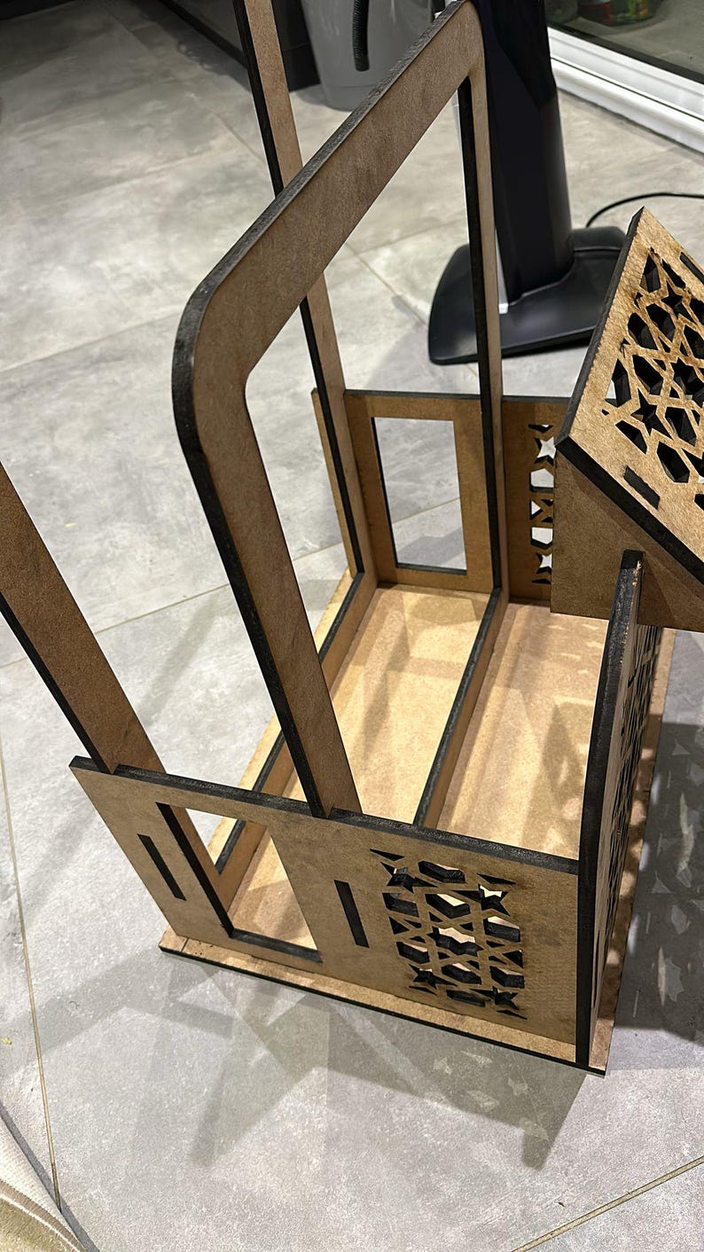 May include: A wooden dollhouse with a brown exterior and intricate cutouts. The dollhouse has two levels and a small balcony. The dollhouse is made of plywood and has a natural wood finish.