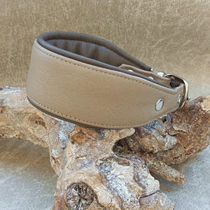 Könnte beinhalten: Ein hellbraunes Lederhundekragen mit einem dunkelbraunen Lederfutter. Das Halsband hat eine silberne Schnalle und einen silbernen D-Ring.