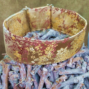 May include: A gold and red floral patterned dog collar with silver hardware.