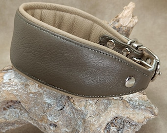 May include: A wide, taupe-colored leather collar with a beige interior lining. The collar features visible stitching along the edges, a silver-toned metal buckle, and a single silver-toned rivet on the side for secure fastening.