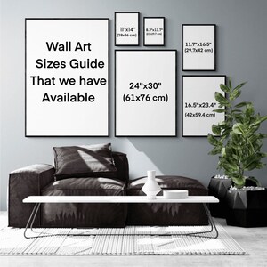 May include: Wall art sizes guide with different sizes listed in inches and centimeters. The guide is displayed on a wall with a couch and a plant in front of it.