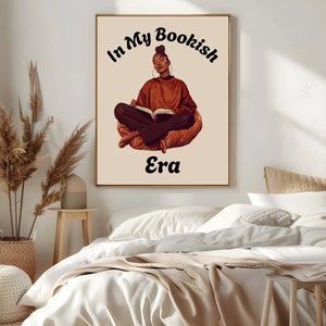 Op de afbeelding: Een digitale illustratie van een vrouw die in een zitzak zit en een boek leest. De tekst "In My Bookish Era" staat boven haar. De achtergrond is lichtbeige.