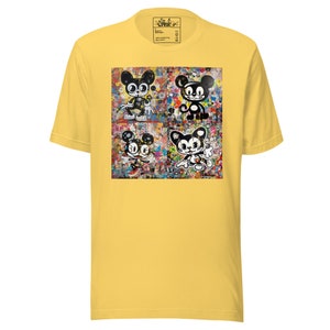 May include: Yellow t-shirt featuring a colorful graphic of four cartoon characters with black and white details. The graphic is set against a background of abstract paint splatters. The shirt has a crew neck and short sleeves.