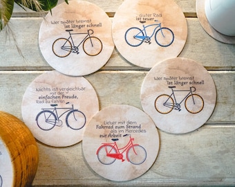 May include: Set of six round coasters with a brown background and black bicycle illustrations. Each coaster features a different saying about cycling, including "Wer später bremst ist länger schnell" (German for "Whoever brakes later is faster for longer") and "Guter Rad ist teuer" (German for "Good bike is expensive").