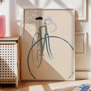 Könnte beinhalten: Abstrakter Kunstdruck mit einer Fahrradillustration. Das Kunstwerk verwendet einen minimalistischen Stil mit blauen, grünen und schwarzen Pinselstrichen auf beigem Hintergrund. Die Form des Fahrrads wird durch einfache Linien und Formen angedeutet, gerahmt in einem weißen Rahmen.